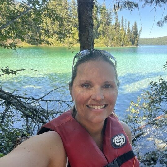 woman smiling in front of a lake